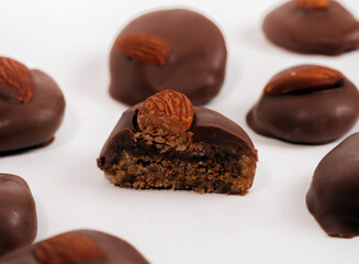 chocolate pieces with almond or walnut over in box or on table,one over another in pyramid.sweets candy on white surface,free space for text, ready for chocolate business or factory.