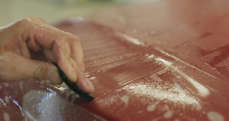 professional applying protective film to the red car