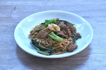 stir fried vermicelli rice noodles with slice fermenting pork and Chinese kale dressing black sweet soybean sauce on plate