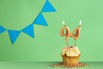 Birthday card with number 94 candle - Cupcake on a green background with blue pennants.