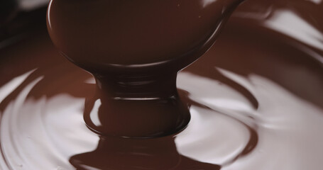 closeup pouring melted dark chocolate from spoon