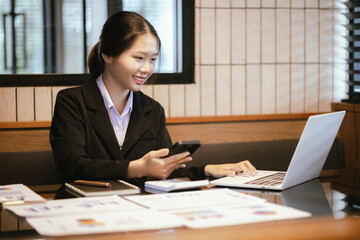 Young asian businesswoman analyzing financial chart using digital tablet and calculator in office