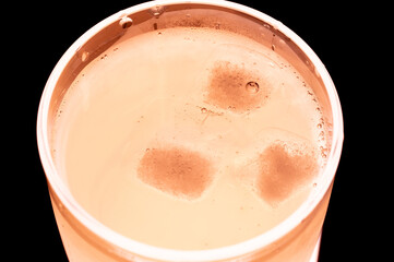 A beverage  with ice cubes, diagonally from above and very close up so that you can see the carbon...
