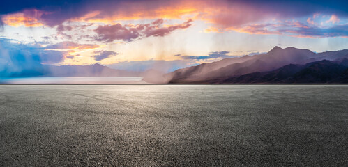 Asphalt road square and lake with mountain nature landscape at sunset. It's raining in the distance. Car advertising background.