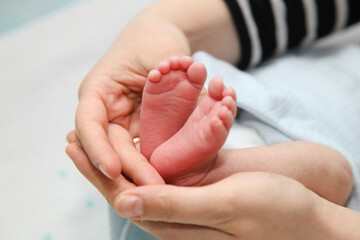 Mother holding newborn baby feet in hands