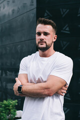 Confident young man standing against building in street