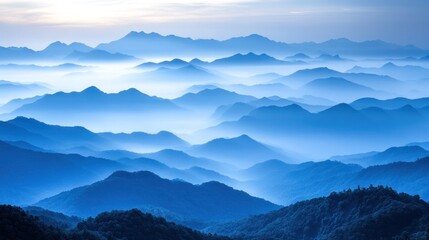 Obraz premium A panoramic view of a misty mountain range with a blue sky and layered mountains, creating a sense of depth and vastness.