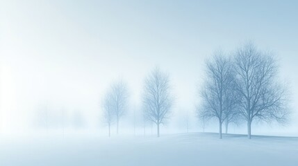 A row of bare trees stand silhouetted against a hazy, blue sky.  The landscape is shrouded in mist, creating a sense of mystery and tranquility.