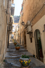 Narrow street in the old town of Cefalu in Sicily, Italy in a beautiful summer day. Travel and sightseeing journey concept