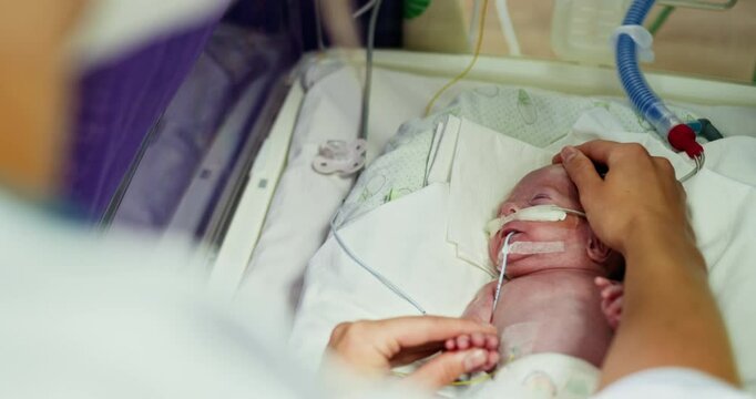 A healthcare professional is providing care for a premature infant in a neonatal intensive care unit. A Tender Moment Shared Between a Loving Parent and Their Newborn Baby in the NICU