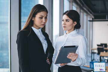 Focused female colleagues using tablet