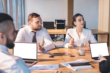 Fototapeta premium Team of intent coworkers having discussion and using laptop at meeting in conference room
