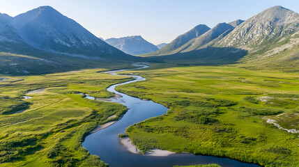 Fototapeta premium Aerial view of a winding river flowing through a lush valley surrounded by majestic mountains.