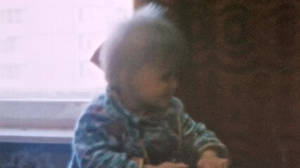 Small child exploring new things, sewing machine. Curious baby learning about world. Active development in childhood. Kid creativity playing game with household items. Vintage film. Retro 1980 archive
