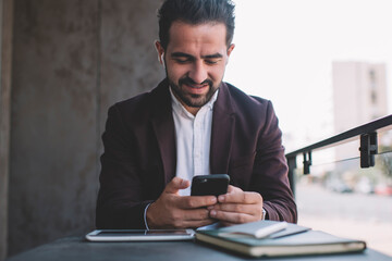 caucasian man in formal wear on coffee break sending text messages online enjoying radio via wireless bluetooth accessory, smiling successful male manager read news and listen music on cellphone