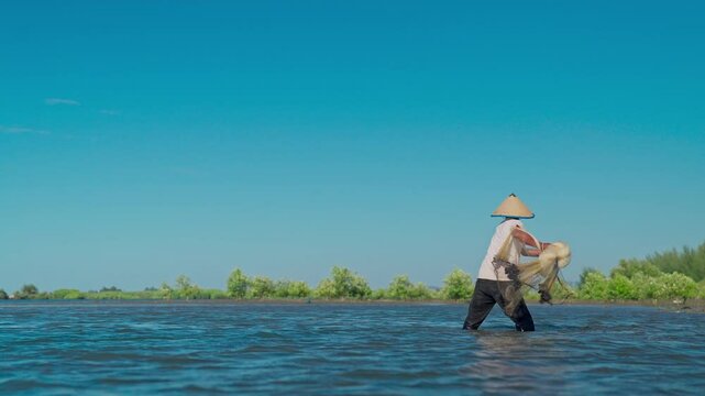 A fisherman throwing a fishing net on the seashore