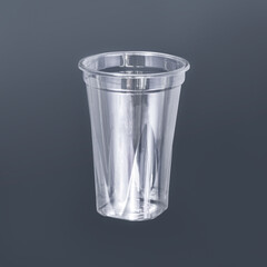 Photo of a disposable clear plastic cup on a dark background. Subject photography.