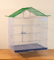 A large empty metal cage for birds on a wooden table