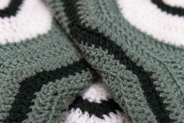 close-up of folded sage green zigzag blanket with white and hunter green accents, crocheted or knitted, reminds you of grandma's house, cozy and warm background