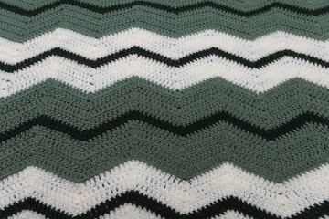 close-up of grandma's retro zigzag striped blanket, in white, dark green and sage green, crocheted or knitted, grandma's house, cozy and warm, horizontal