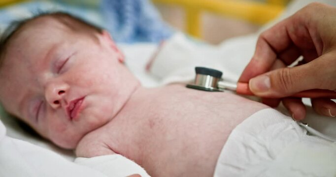 A healthcare professional assesses a newborn using a stethoscope in a hospital setting. Conducting a comprehensive health check for newborns in the neonatal unit is essential