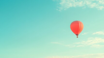 Obraz premium A single red hot air balloon floats in a clear blue sky with white clouds, the perfect image of freedom and adventure.