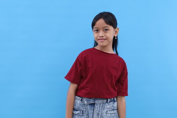 Adorable asian little girl standing while smiling. Isolated on blue background