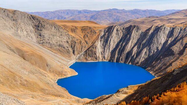 Bright blue volcanic crater lake landscape. Orange mountains and hills. Cinematic unusual touristic destination. Aerial shot of a unique terrain. Untouched Icelandic nature. Panoramic view.