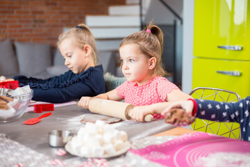 Sisters rolling cookie dough making festive cookies at home
