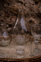 Old glass containers. Collection of retro bottle, amphorae and glasses placed on a wicker tray.