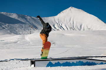 Snowboarder executes seated trick on challenging wallride with impressive style.
