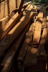 pile of old waste wood planks from construction or demolition site, stack of trash wood with nails splinters, close-up garbage heap in selective focus