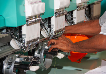 embroidery machine multiple head industrial, african american worker in a apparel textile factory