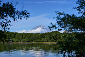 Koryak volcano. A serene view of a majestic mountain mirrored in tranquil lake waters, surrounded...