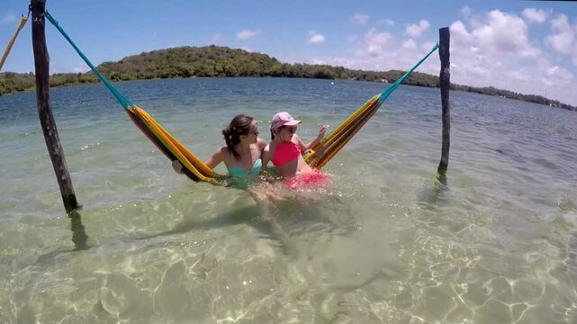 m&atilde;e  e filha em rede nas f&eacute;rias de ver&atilde;o em linda lagoa de &aacute;guas limpas 