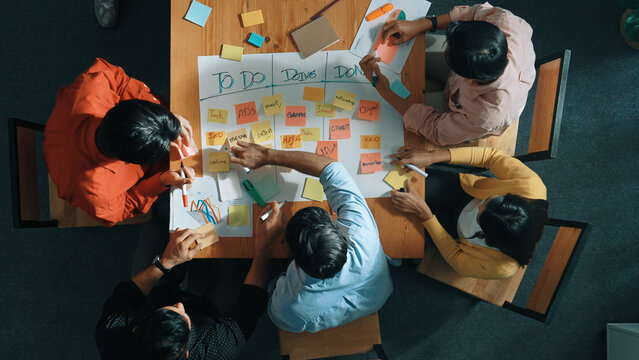 Top view of people writing and making scrum task board while writing marketing and planning strategy at colorful sticky notes. Smart team manage work performance by using kanaban board. Convocation.