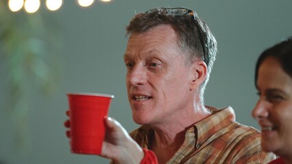 Family together for holiday celebration. Old senior couple cheers with beverage glass drinking to celebrate in party. Outdoor camping activity eating food and spend time with relatives. Divergence.