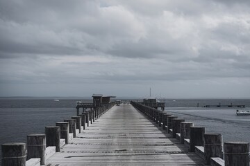 Fototapeta premium A long wooden pier extending into a body of water under an overcast sky