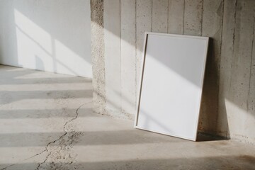 Minimalist blank poster with frame on textured concrete wall and floor in natural light