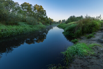 A river with a blue water and green grass