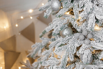 A Christmas tree sprinkled with artificial snow in the New Year's interior. Background for New Year wallpapers and postcards.