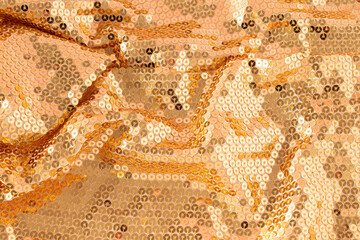 Glamorous golden metallic glowing sequins textile with pink reflection background. Christmas holiday or New Year party concept. Abstract luxury glowing textured background.
