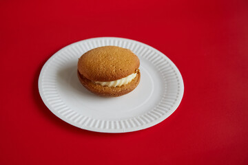Pumpkin pie with cream on a white disposable plate against a red background, autumn sweet dessert, pumpkin dessert.