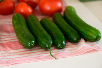 Fresh cucumbers and ripe tomatoes arranged artistically on a kitchen countertop during a sunny afternoon