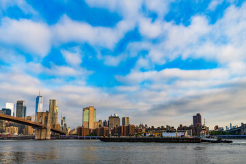 Naklejka premium Brooklyn bridge of New York city. Brooklyn landmark. Manhattan cityscape with skyscraper architecture. Brooklyn bridge to Manhattan. Urban architecture of New York city. Tugboat and barge