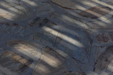 Shadows play on a rustic stone path under warm afternoon light in a serene outdoor setting