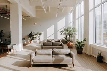 Modern Office Lounge with Natural Light and Plants.  A contemporary office lounge area featuring a minimalist aesthetic, with beige couches and chairs arranged around potted plants. 