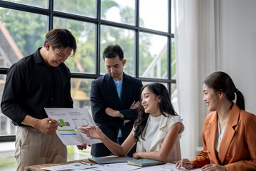 Asian business team analyzing financial charts and business growth in modern office meeting room