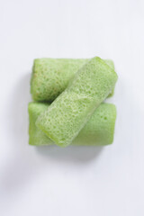 Traditional Indonesian food called 'Dadar Gulung', an elliptical cake filled with grated coconut and liquid palm sugar, isolated on a white background.