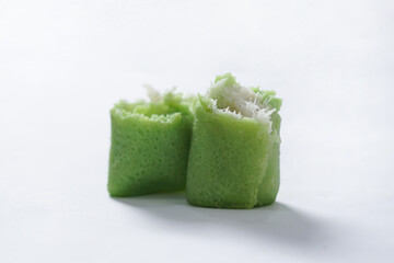 Traditional Indonesian food called 'Dadar Gulung', an elliptical cake filled with grated coconut and liquid palm sugar, isolated on a white background.